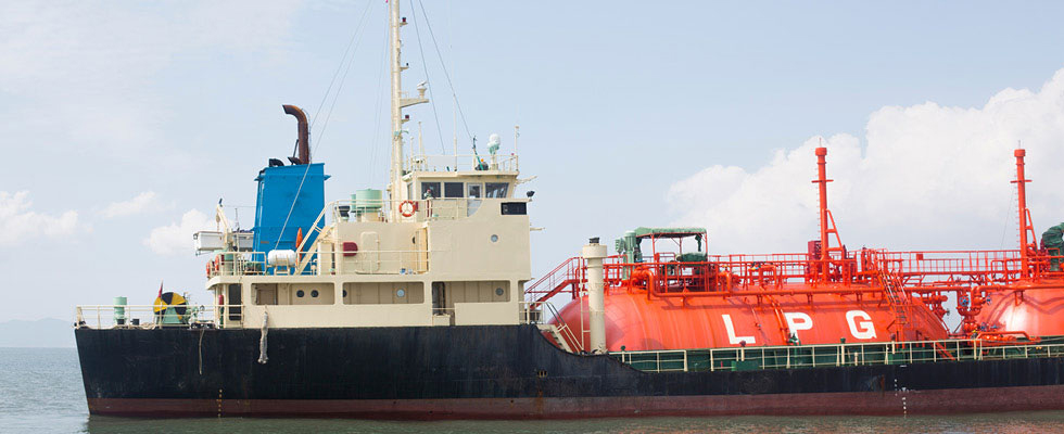 A ship transports LPG in large orange tanks on deck