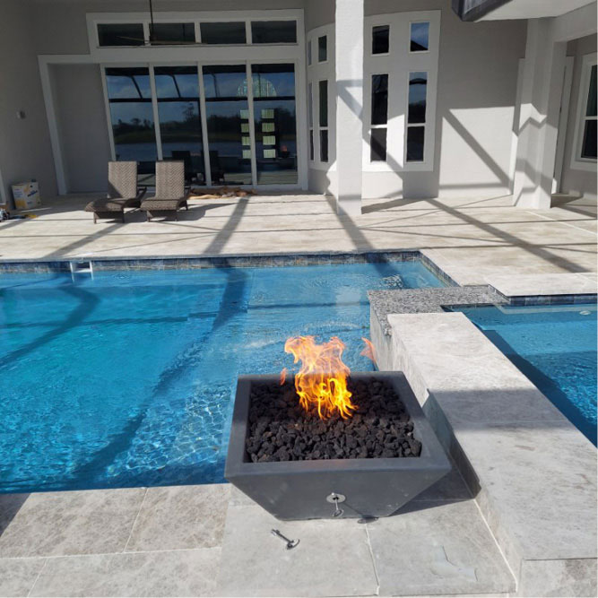 A patio fireplace by a pool running off of propane