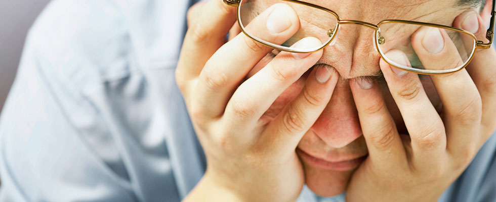 A stressed man covers his eyes 