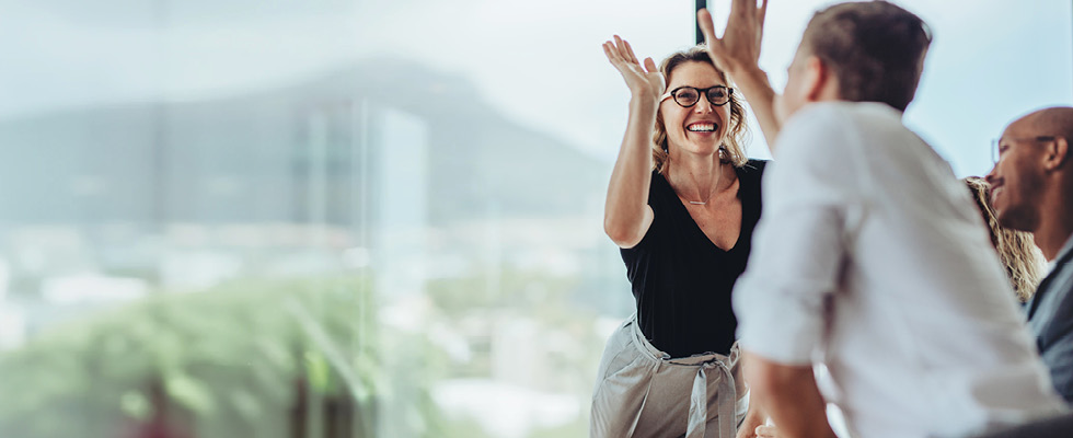 A man and woman in an office setting high-five each other