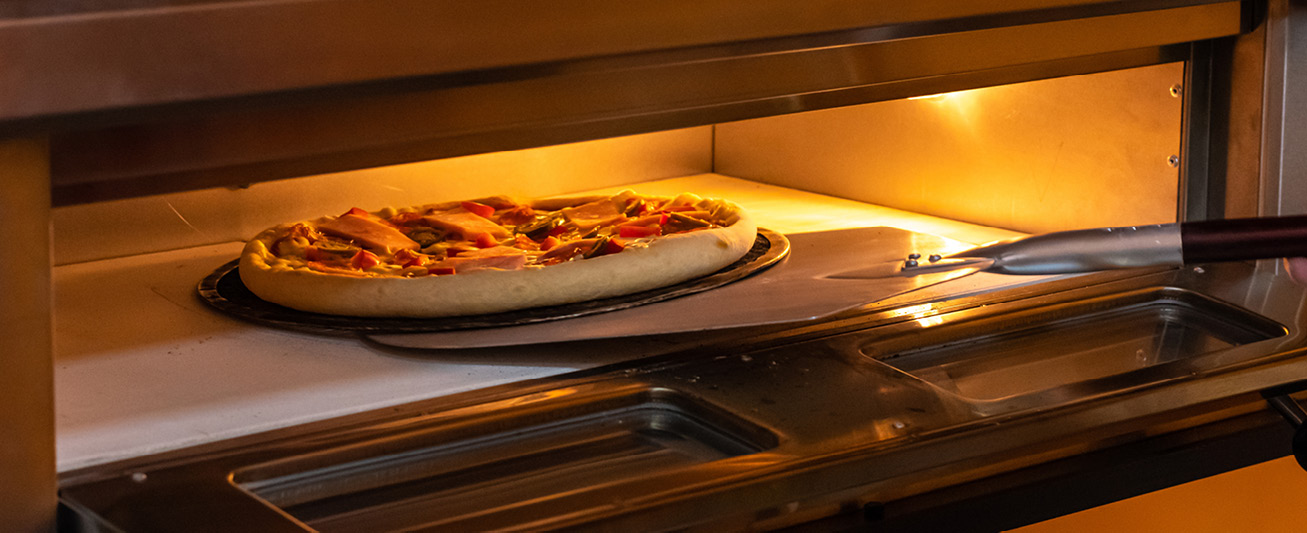 A pizza is placed into an oven.