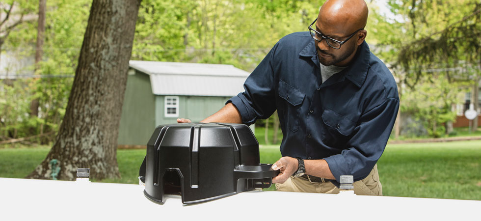 A man works with a propane tank monitoring device