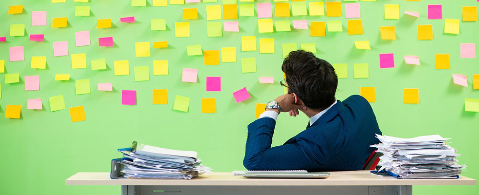 A man looking at a post-it filled wall