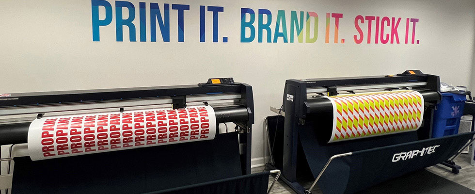 A printing machine is displayed printing off signs and marketing material.