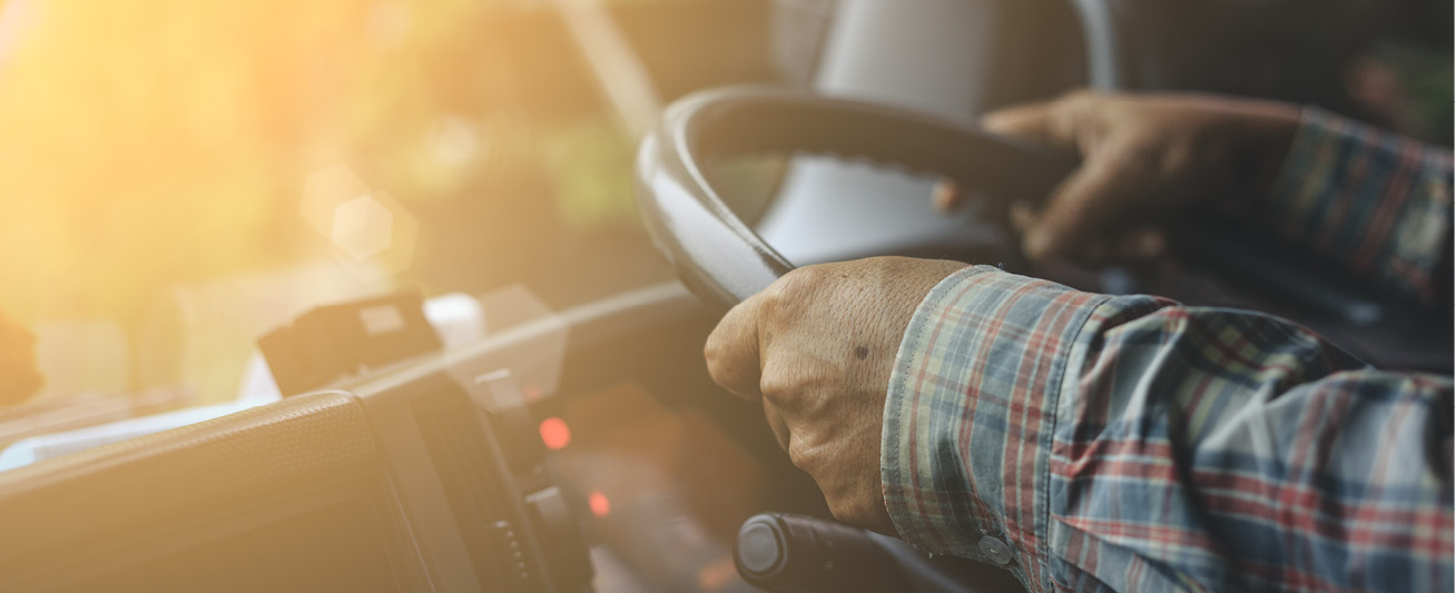 A driver's hands are pictured holding the wheel of a truck.