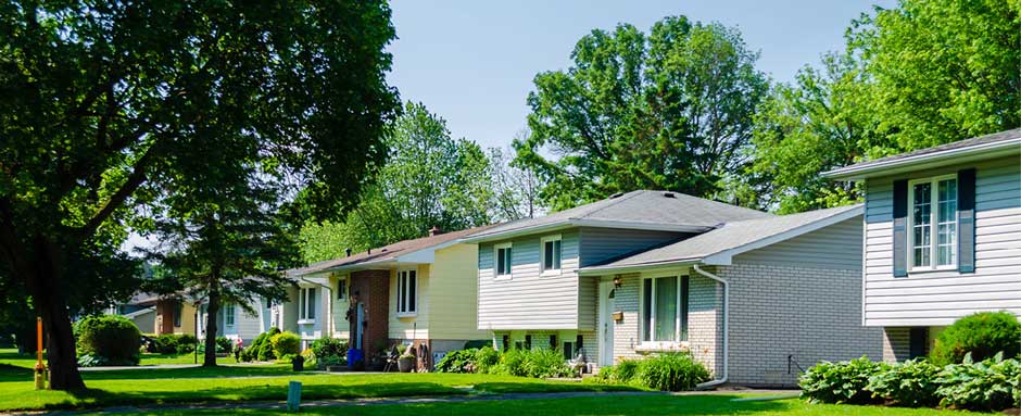 A row of split level houses and trees on a residential street