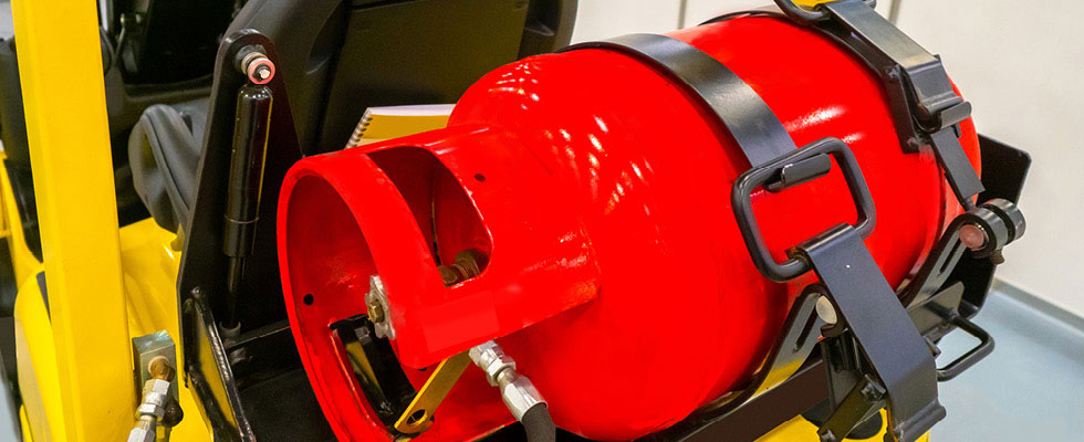 A bright red propane cylinder is pictured situation on the back of a forklift.