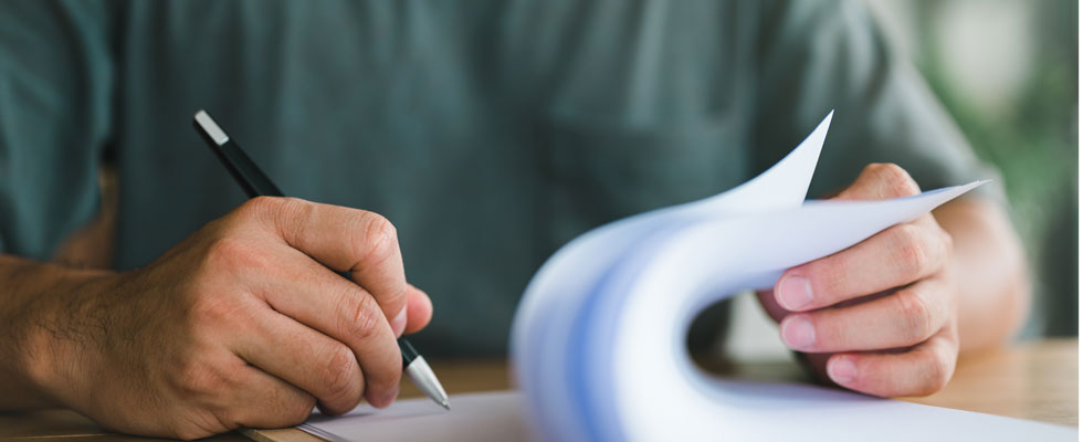 A man fills out and signs a series of forms