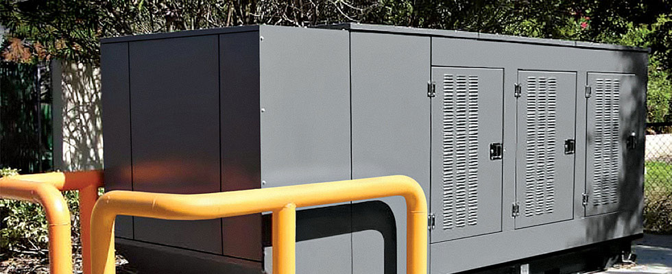 A propane backup generator sits outside by green trees with a yellow safety rail around it