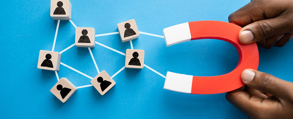 A person holds a horseshoe-shaped magnet that is linked to blocks with face silhouettes