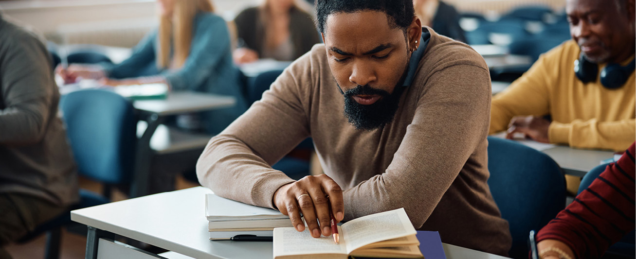 An image of a man looking intently at a book in a classroom reflects the question for this issue of Verbatim.
