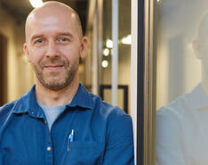 A company leader smiles in his office building